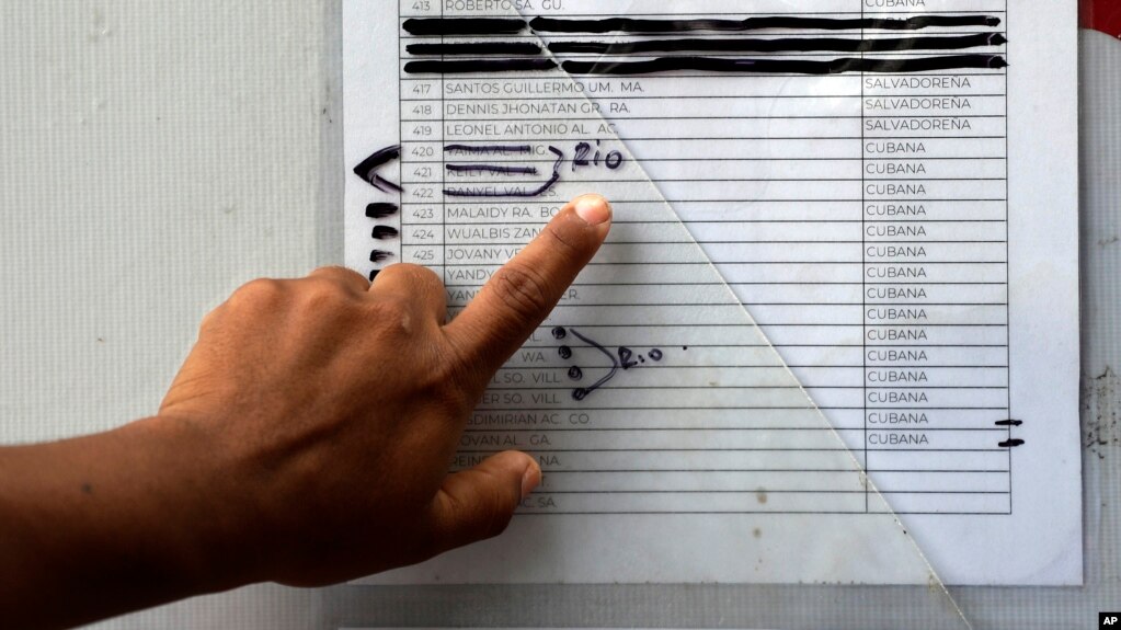 FILE - A migrant in Matamoros, Mexico checks a typewritten list of more than 800 people seeking asylum in the US, April 30, 2019. Those marked with the word rio, Spanish for river, are believed to have crossed the Rio Grande to enter the US without authorization.