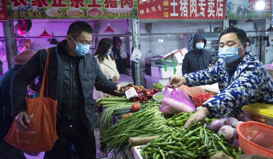 In this photo released by China's Xinhua News Agency, people shop for vegetables at a market in Wuhan in central China's Hubei Province, early Thursday, Jan. 23, 2020. China closed off a city of more than 11 million people Thursday in an unprecedented effort to try to contain a deadly new viral illness that has sickened hundreds and spread to other cities and countries in the Lunar New Year travel rush. (Xiao Yijiu/Xinhua via AP)