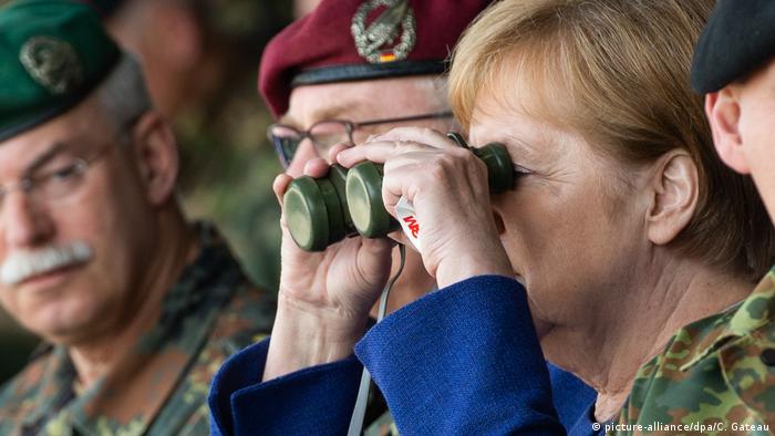 Merkel looks through binoculars at troops in Munster (picture-alliance/dpa/C. Gateau)